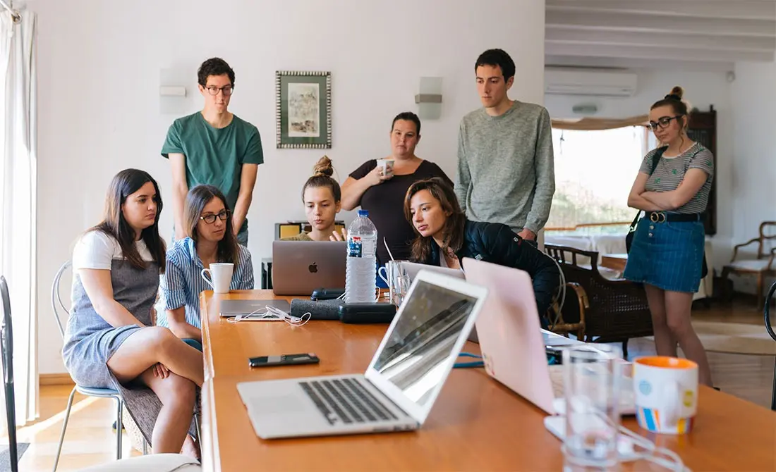 A team of professionals gathered around laptops for a marketing discussion, guided by the best freelance digital marketing analyst in calicut